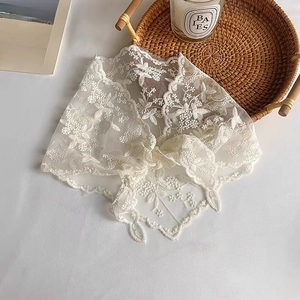 Detailed view of white lace triangle scarf with floral embroidery and scalloped edges