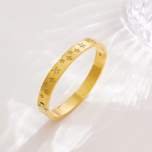 Detail showing gold stainless steel bangle with star engravings and zircon stones