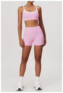 Détail d'un ensemble brassière et short de sport rose avec surpiqûres blanches de yoga