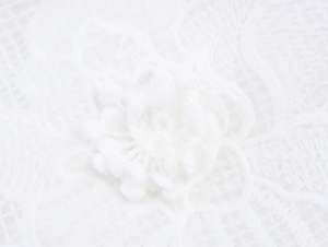 Detailed macro view of white 3D lace flower embroidery on delicate mesh fabric