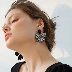 Primo piano di eleganti orecchini a fiocco nero con strass lucidi su una modella donna