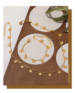 Detailed shot of golden sunflower pendant necklace and matching bracelet on textured background