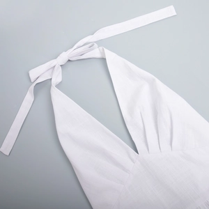 Detailed view of white cotton V-neck halter dress with tie-up bow and pleated texture