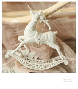 Close-up of a white glitter reindeer rocking horse ornament with silver hanging string