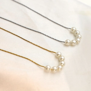 Detailed close-up of gold and silver pearl beaded necklaces on white silk fabric
