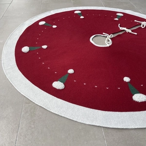 Détail du tapis de sapin de Noël tricoté rouge avec motifs de bonnets à pompons