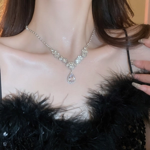 Close-up of model wearing silver teardrop pendant necklace with sparkling crystal flower