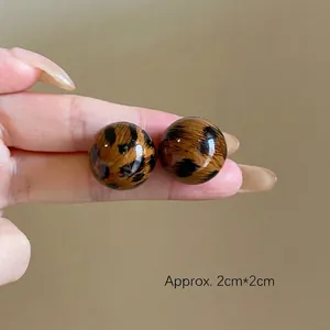 Close-up of leopard print resin ball earrings measuring approximately 2cm by 2cm