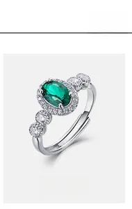 Macro shot of silver ring featuring oval green emerald center stone with diamond halo