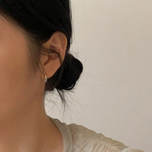 Close-up of minimalist silver zircon hoop earrings worn by a model for a chic look