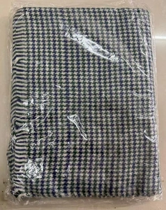 Detail of navy and emerald houndstooth scarf with striped edge in clear packaging