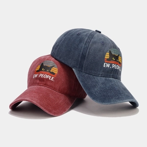 Detail of washed cotton baseball caps in burgundy and navy with cat and sunset print