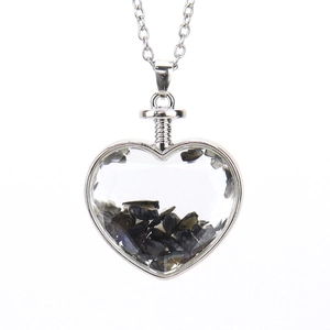 Detail view of heart-shaped glass pendant filled with black natural crushed stones