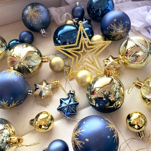 Blue and gold assorted Christmas tree ornaments with stars and balls on a white surface