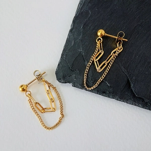 Close-up of dual-layer chain drop earrings in 18k gold finish on a stone texture background