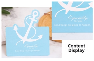 Detail of light blue gift tag with white anchor design and inspirational message on marble
