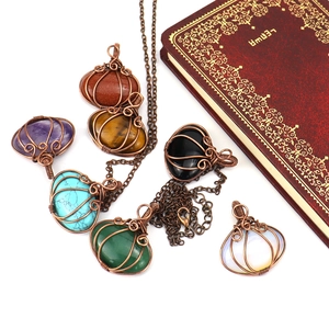 Handcrafted wire-wrapped pumpkin pendant necklaces with natural gemstones on vintage book