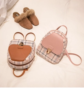 Detailed view of mini backpacks in brown and pink leather with plaid fabric on fabric