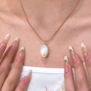 Macro detail of elegant golden snake chain with a white iridescent oval pendant