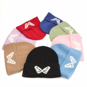 Detail of multi-color knitted beanies featuring white butterfly jacquard patterns