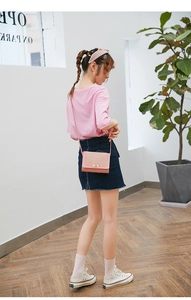 Pink grid texture crossbody bag shown from a side view with a model in an urban setting