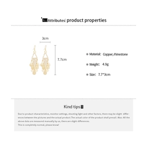 Detailed specs of gold leaf tassel earrings made of copper and sparkling rhinestones