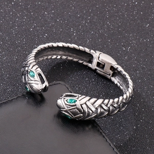Detailed view of silver snake open cuff with green eye accents and textured scales