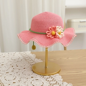 Detail of pink straw sun hat featuring crochet flowers and delicate lace trim on wavy brim