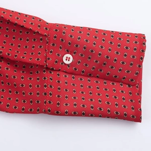 Gros plan détaillé d'un poignet de chemise rouge à motifs géométriques et bouton blanc