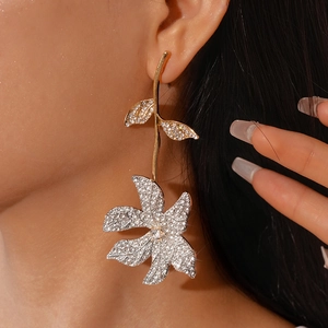 Elegant gold and silver flower drop earrings with sparkling rhinestones worn by a model