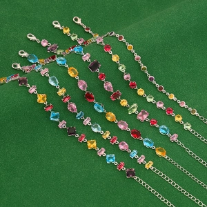 Close-up of sparkling colorful zircon crystal bracelets with various gem shapes on green fabric