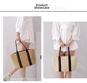 Straw tote bag with black straps and large capacity shown on model in a soft-lit room
