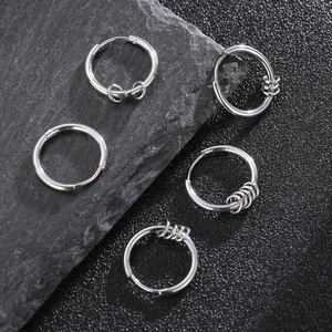 Close-up of five silver stainless steel hoop earrings on a textured dark grey stone slab