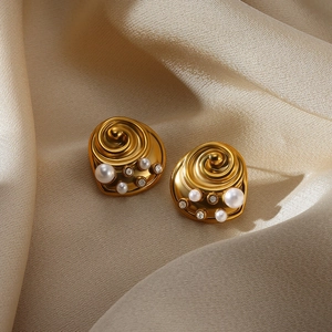 Detail of vintage gold swirl earrings with white pearls and sparkling zircons