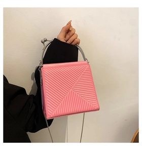 Detail of pink quilted handbag with geometric stitching and silver metal handle