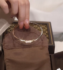 Detailed close-up of a gold knot bracelet with micro-pave zircons held in a velvet pouch