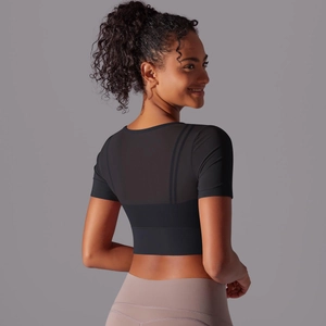 Close-up of mesh splicing detail on back of black cropped sports top for women
