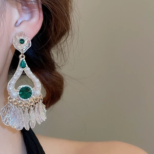 Detail of vintage gold drop earrings with green gems, pearls and leaf-shaped tassels