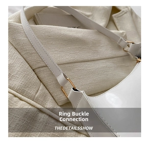 Detail of white patent leather shoulder bag showing golden D-ring hardware and stitching