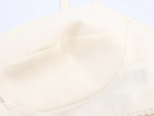 Macro view of beige linen-textured fabric showing stitching details on crop top