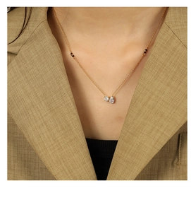 Detail of gold necklace featuring two pear-shaped crystals and small black accent beads