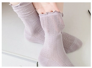 Detail of light purple mesh socks with lettuce trim cuffs worn with elegant black shoes