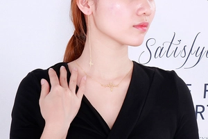 Close-up of a model wearing golden heartbeat pattern necklace and lightning ear wire set