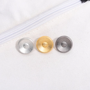 Three metallic round buttons in silver, gold and dark gray on white canvas fabric