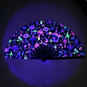 Detail of UV reactive folding fan with neon mushroom patterns glowing under purple light