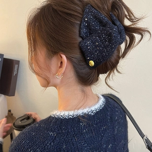 Close-up of navy tweed bow hair claw with silver sequins and golden metal button