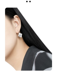 Macro side view of a model wearing silver square stud earrings with lava texture surface