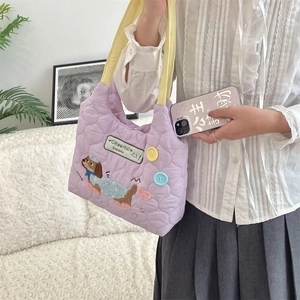 Detalle del bolso acolchado lavanda con bordado de perro, asas amarillas y botones de colores