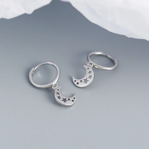 Macro detail of S925 silver hoop earrings with hollow star and crescent moon pendants