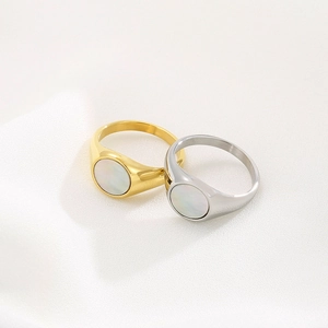 Detail view of gold and silver minimalist rings with white shell inlay on white silk fabric